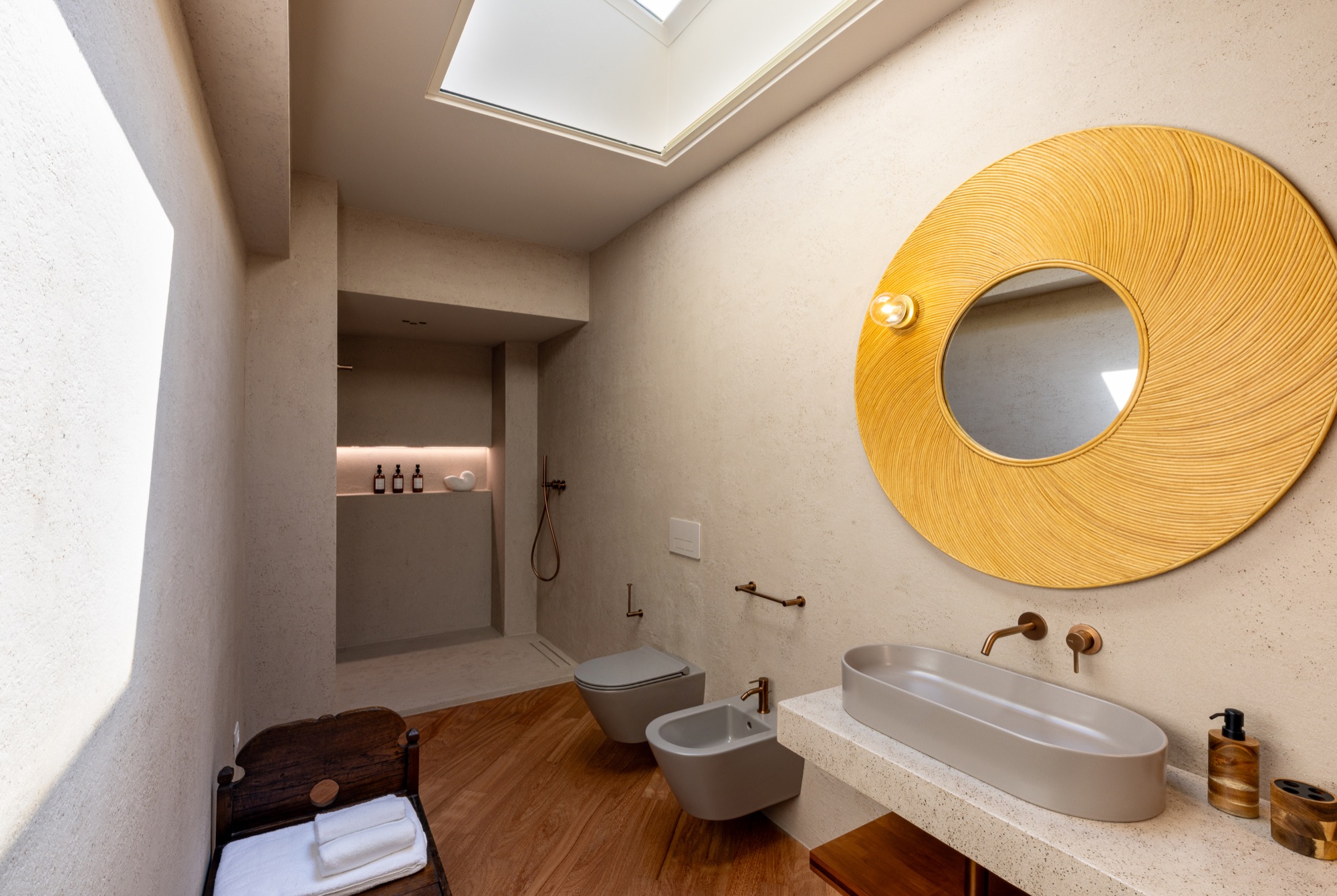 Lavabo in resina con grande specchio rotondo in fibra naturale, doccia Fima Waterdot in fondo