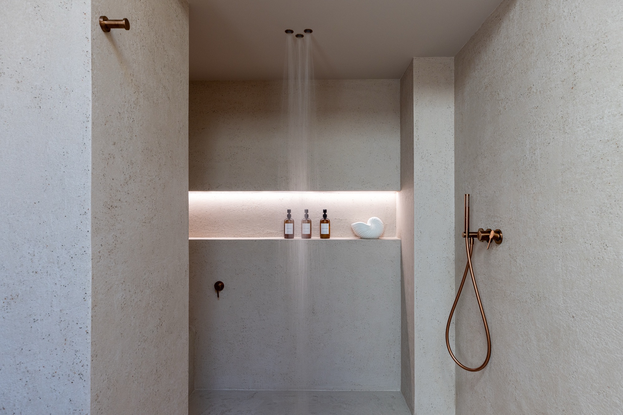 Ambiente doccia con sistema Fima Waterdot, tre soffioni a soffitto in azione e nicchia retroilluminata